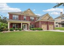 Charming two-story brick home with a well-manicured lawn and attached two car garage at 2120 Cain Commons Dr, Dacula, GA 30019
