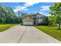 Charming home featuring a well-maintained lawn, long driveway, and attached garage at 2102 Braswell Ln, Loganville, GA 30052
