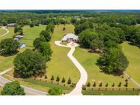 Expansive estate with a brick home, winding driveway, and lush green lawn in a serene, wooded setting at 3030 Berry Rd, Loganville, GA 30052