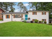 Charming white brick home featuring a manicured lawn, blue front door, and contrasting black trim at 2240 Clanton Ter, Decatur, GA 30034