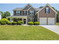 Charming two-story home featuring manicured lawn, stone accents, and a welcoming covered front porch at 868 Cork Oak Ln, Lawrenceville, GA 30045