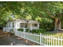 Charming cottage-style home with a white picket fence and mature trees providing ample shade at 311 Henry Aaron Ave, Atlanta, GA 30310