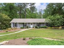 Charming single-story home with gray siding, black shutters, a well-manicured lawn, and mature trees at 3131 Garden Lane Dr, Marietta, GA 30062