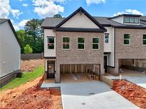 New construction townhome featuring a brick facade, attached two-car garage and modern design elements at 5720 Urban Village Way # 7, Tucker, GA 30084