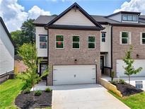 Charming new construction townhome featuring a brick facade and a two-car garage and well-manicured lawn at 5720 Urban Village Way # 7, Tucker, GA 30084
