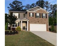 Inviting two-story home featuring a brick and siding facade, manicured lawn, and a two-car garage at 9405 Bandywood Dr, Covington, GA 30014