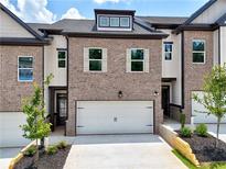Charming brick townhouse with white trim, a two-car garage, and manicured landscaping at 5722 Urban Village Way # 8, Tucker, GA 30084