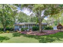 Charming single-story home with blue siding, a lush lawn, mature trees, and well-maintained landscaping at 1588 Peachtree Cir, Lawrenceville, GA 30043