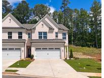 Charming brick townhome featuring a two-car garage and well-manicured lawn at 4180 Cavalier Way, Duluth, GA 30097