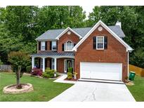 Charming brick home featuring a covered front porch and well-manicured lawn at 4613 Creek Forest Ct, Lilburn, GA 30047