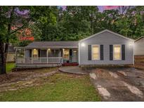 Charming single-story home with a covered porch, gray siding, and driveway leading to the house at 7845 Chase Woods Dr, Jonesboro, GA 30236
