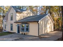 Two-story home with a driveway, tan siding and black trim and windows surrounded by trees at 7156 Whitfield Dr, Riverdale, GA 30296