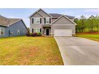 Charming two-story home featuring a gray exterior, manicured lawn, and a concrete driveway leading to a two-car garage at 209 Shelton Cir, Temple, GA 30179
