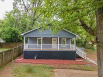 Charming gray house with a cozy front porch and neat landscaping, surrounded by mature trees at 1889 Vesta Ave, Atlanta, GA 30344