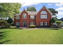 Traditional brick home with a well-maintained lawn and mature landscaping at 6355 Stallion Dr, Cumming, GA 30040