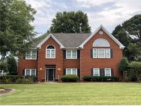 Charming two-story brick home with a well-manicured lawn and mature trees in a peaceful neighborhood at 6355 Stallion Dr, Cumming, GA 30040