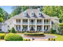 Elegant white home featuring a symmetrical design, stately columns, and mature landscaping at 5045 Harrington Rd, Johns Creek, GA 30022