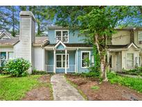 Charming two-story home with light blue siding, white trim, covered porch, and mature trees at 2261 Wellington Cir, Lithonia, GA 30058