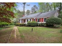 Charming one-story brick home with lush landscaping and a brick pathway to the front door at 491 Hemlock Sw Dr, Marietta, GA 30064