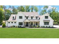 Stunning two-story white farmhouse with black trim, a sprawling lawn, and professionally landscaped gardens at 604 Trinity Church Rd, Canton, GA 30115