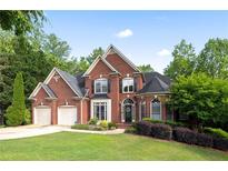 Charming two-story brick home with lush landscaping and a two-car garage at 417 Rhodes House Dr, Suwanee, GA 30024