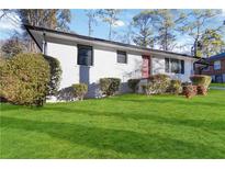 Charming, freshly painted home with a manicured lawn and vibrant red door, complemented by mature landscaping at 1796 Arkose Se Dr, Atlanta, GA 30316