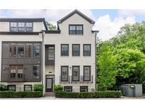 Beautiful three-story townhome featuring a painted brick exterior, dark window trim, and manicured landscaping at 4538 Collins Ave, Sandy Springs, GA 30342