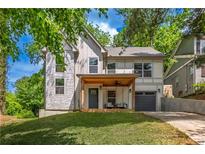 Charming two-story home with a stone facade, covered porch, and attached garage on a lush, green lot at 82 Dearborn Se St, Atlanta, GA 30317