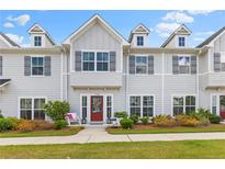 Charming townhome with gray siding, dormer windows, and a welcoming red front door with stylish landscaping at 1700 Prospect Way, Conyers, GA 30094