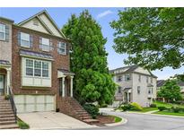 Charming brick townhome featuring a two-car garage, lush landscaping, and a welcoming entrance staircase at 2143 Yancey Ne Ln, Atlanta, GA 30319