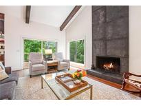 Inviting living room featuring a stone fireplace, wood beams, and large windows with a view to a wooded yard at 2075 Six Branches, Roswell, GA 30076