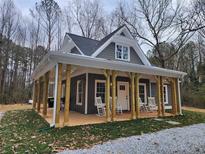 Charming gray home featuring a welcoming front porch with rocking chairs and a gravel driveway at 40 Luther Knight Se Rd, Cartersville, GA 30121