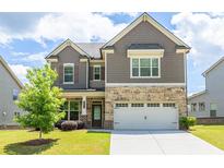Charming two-story home with stone accents and a well-manicured lawn under a bright, partly cloudy sky at 3477 Ivy Birch Way, Buford, GA 30519
