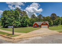 Charming red brick home featuring a well-manicured lawn and mature trees at 265 Oak Hill Dr, Covington, GA 30016