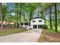 Charming split-level home boasts a two-car garage and mature trees on a lovely, landscaped lot at 671 Shannon Green Sw Cir, Mableton, GA 30126