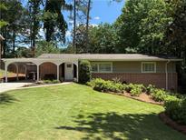 Charming brick home with manicured lawn, lush landscaping, and covered carport in a desirable neighborhood at 3533 Keswick Dr, Atlanta, GA 30341