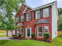 Charming two-story red brick home with a manicured lawn and a two-car garage at 1185 Charter Club Dr, Lawrenceville, GA 30043