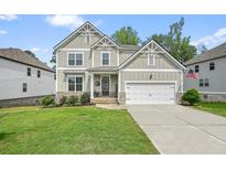 Charming two-story home with well-manicured lawn and inviting front porch, displaying a modern and clean exterior design at 6915 Rambling Vale, Cumming, GA 30028
