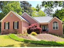 Charming brick home with manicured lawn and black shutters nestled among mature trees at 1510 Heritage Dr, Cumming, GA 30041