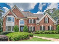 Elegant two-story brick home featuring manicured landscaping and a classic architectural design at 9810 Foxworth Dr, Alpharetta, GA 30022