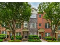 Charming townhouses feature varied brick and stone facades, complemented by lush green trees and manicured landscaping at 1227 Ashford Creek Ne Park, Atlanta, GA 30319