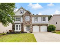 Charming two-story home with stone accents, a well-manicured lawn, and a two-car garage at 935 Mill Creek Ave, Canton, GA 30115
