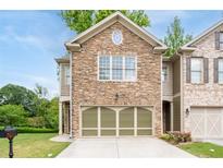 Charming townhome featuring a stone facade, attached two-car garage, and well-maintained landscaping at 4023 Caitlyn Pl, Atlanta, GA 30360