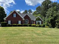 Charming brick home featuring a well-manicured lawn and lush landscaping in a peaceful residential neighborhood at 4530 Bogan Gates Dr, Buford, GA 30519