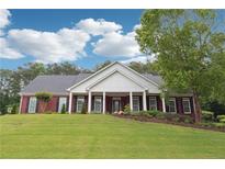 Charming brick home featuring a manicured lawn, black shutters, and a covered front porch at 825 Kennedy Ct, Loganville, GA 30052