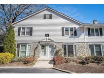 Charming townhome featuring white siding, stone accents, black shutters, and a well-maintained front yard at 136 Peachtree Memorial Nw Dr # Va2, Atlanta, GA 30309