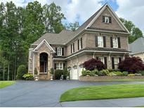 Beautiful brick home with a well-manicured lawn, lush trees, and an expansive driveway at 608 Tabbystone Nw St, Marietta, GA 30064