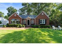Charming brick home featuring a beautifully landscaped front yard with inviting Adirondack chairs and lush green grass at 615 Wilson Nw Rd, Atlanta, GA 30318