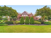 Elegant brick home with manicured lawn and mature trees, offering privacy and curb appeal at 692 Heritage Post Ln, Grayson, GA 30017