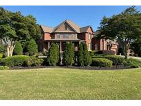 Expansive brick home with manicured landscaping, mature trees, and lush green lawn at 692 Heritage Post Ln, Grayson, GA 30017